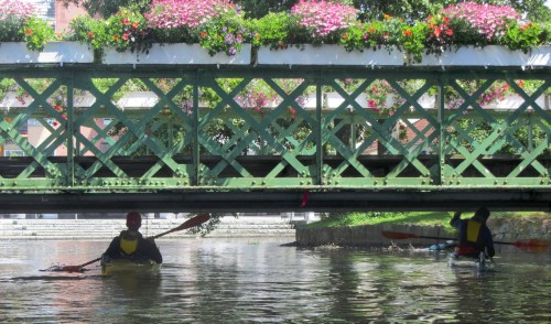 Jakob och David duckar för att glida under en gammal, vacker och blomsterprydd gångbro